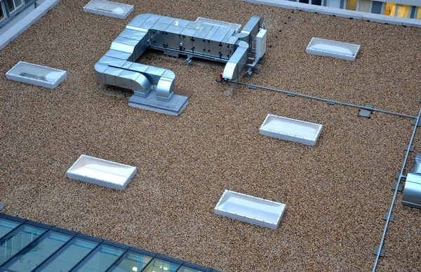 gravel mulch on roof of a flat green roof. covers and protects layers of insulation, decorative effect. exhaust from kitchen evaporators, turbo gas boiler chimney. air conditioning outlet, pebble