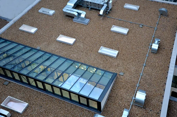 gravel mulch on roof of a flat green roof. covers and protects layers of insulation, decorative effect. exhaust from kitchen evaporators, turbo gas boiler chimney. air conditioning outlet, pebble