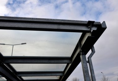 strut, suspended glass roof above the building entrance. bus station, railway station. cable wind braces. aluminum construction with windows above pergola  galvanized steel frame