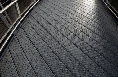 staircase and wide pedestrian bridge with perforated metal floor. galvanized sheet metal with circular holes. white railings like on a ship in the arch. handrail made of polished stainless steel pipe.