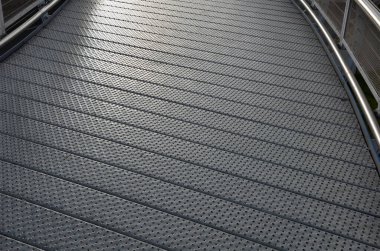 staircase and wide pedestrian bridge with perforated metal floor. galvanized sheet metal with circular holes. white railings like on a ship in the arch. handrail made of polished stainless steel pipe.