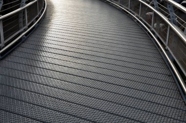 staircase and wide pedestrian bridge with perforated metal floor. galvanized sheet metal with circular holes. white railings like on a ship in the arch. handrail made of polished stainless steel pipe.