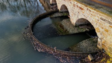 drive of the mill under bridge. water is filtered through sieve grid so that farmed fish do not swim away. water purification from floating dirt on the weir dam, breeding fish pond has canal overflow