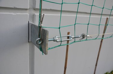 metal trellises made of interconnected stainless steel cables attached to the wall of house grow and wrap vine. column tunnel. detail of mesh clamps, grip, holder, twisted, creeper, fallen tree