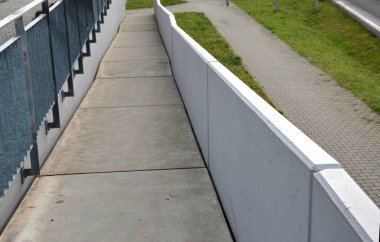wheelchair ramp and stairs on the other side. height differences are tastefully and functionally solved by a retaining wall with a glass railing. city stairs with recessed lights park lawn handlebar