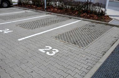 new infiltration parking lot made of porous concrete tiles in a regular square grid with holes filled with gravel. in connection with the asphalt road and the sidewalk with interlocking paving