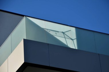 railing of a luxury house consisting of glass panels fastened with gray metal stainless steel paneling. the milky frosted glass barrier gives an airy impression. polished metal cover, rope shadow