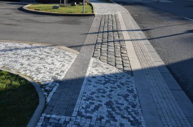connecting two roads running perpendicular to each other. separation of main and secondary roads is by means of raised threshold or ramp made of paving stones and indented tiles with peo bling project