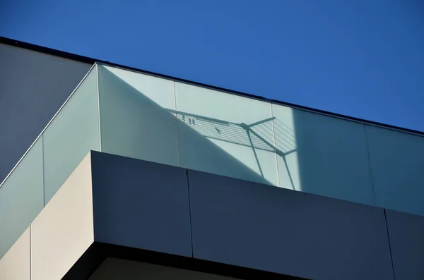 railing of a luxury house consisting of glass panels fastened with gray metal stainless steel paneling. the milky frosted glass barrier gives an airy impression. polished metal cover, rope shadow