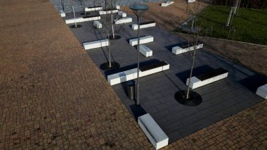 Beton beyaz bank bloğu ve parkta dalga şekli koyu renkli bir meydanda, temiz beton yüzey gri kahverengi beyaz yayalar ve kaykay parkında gençler için dinlenme alanı.