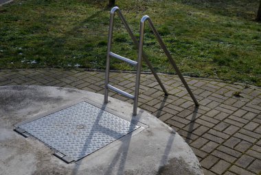 a hinged hatch with a patent lock to the underground of the city, where there are collector shafts with engineering networks. or the facility and subway entrance directly sidewalk ladder, entrance