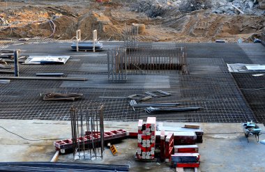 Bir mikser ve hortumla pompa yardımıyla yeraltı garajlarının zeminini somutlaştırmak. Beton takviye kabloları gri bir örgüye dolanmış. Büyük binaların monolitik yapıları