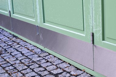 Sheet metal protection of the lower part of the wooden door. trampling with shoes, shopping carts, a wheelchair can damage the new green door of a historic building. metal strip attached to floor, rub