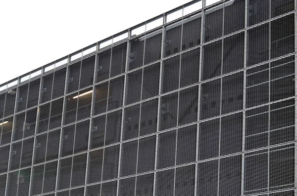 steel cladding of a building with a expanded metal lattice structure. galvanized gray nets protect the industrial building. Blue sky in contrast to a silver background