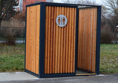 closing cage for placing chemical toilets. unsightly plastic boxes are inside metal house with flat roof and wooden slats on walls. athletes in park or mothers with children can pee, wash hand, event