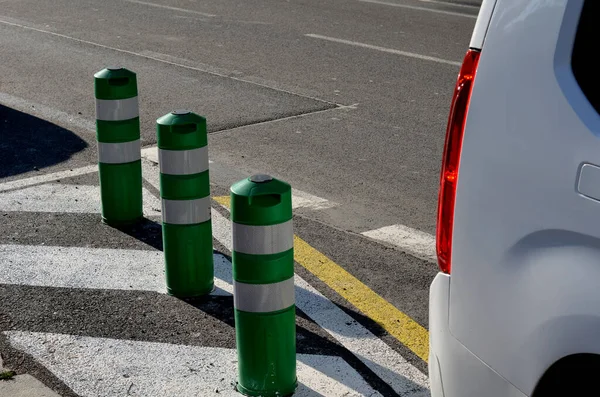 plastic barriers in the form of plastic bollards. they have a preventive effect, but can be bent and possibly run over by car. man tries to bend his hand down to the ground. Ideal deterring vehicle