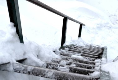 rocky outcrops with a view of the landscape. natural boulder rock completely covered with snow. climbing a frozen metal ladder. handrails made of simple pipes. built by a mountain tourist association