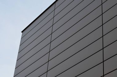 cladding of a building with a expanded metal lattice structure. galvanized gray nets protect the industrial building. Blue sky in contrast to a silver background, wall, corner, slanted, sheet metal