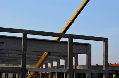 construction of concrete structure of industrial hall of warehouse. the concrete feeder arm from the mixer bends over the beams and columns. pipe conveyor on the crane.excavator, tractor, yellow