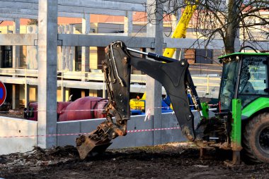 construction of concrete structure of industrial hall of warehouse. the concrete feeder arm from the mixer bends over the beams and columns. pipe conveyor on the crane.excavator, tractor, yellow