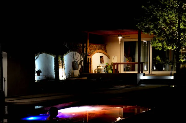 stock image backlit swimming pool frozen in ice in winter. an ideal bath after a sauna ritual. illuminated outdoor walls at night, a greenhouse with a pine tree and a terrace with a pergola, spotlight, brick arch