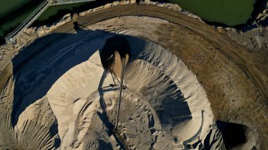 Açık çukur kum madeninin Arial manzarası. Bir ön yükleyici yığınlardan kum yükler. Taş ocağında çalışan ağır madencilik makineleri. Bir sürü tekerlek izi ve çöl kum tepeleri ya da göğüsler gibi kum yığınları, kuru, kumlu, satılıyor.