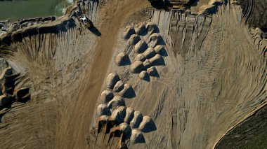 Açık çukur kum madeninin Arial manzarası. Bir ön yükleyici yığınlardan kum yükler. Taş ocağında çalışan ağır madencilik makineleri. Bir sürü tekerlek izi ve çöl kum tepeleri ya da göğüsler gibi kum yığınları, kuru, kumlu, satılıyor.
