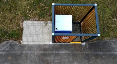 closing cage for placing chemical toilets. unsightly plastic boxes are inside metal house with flat roof and wooden slats on walls. athletes in park or mothers with children can pee, wash hand, event