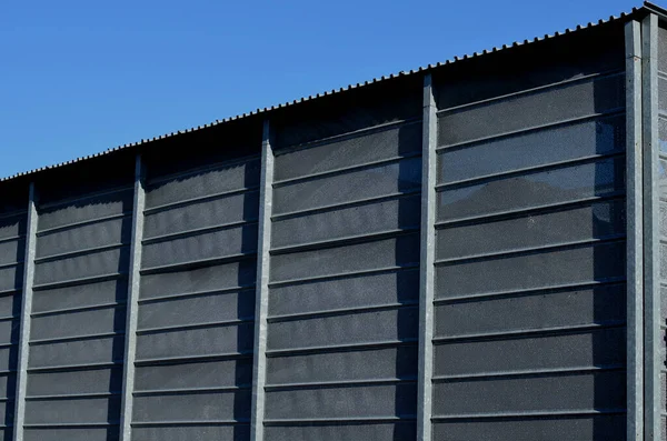 steel cladding of a building with a expanded metal lattice structure. galvanized gray nets protect the industrial building. Blue sky in contrast to a silver background, warehouse