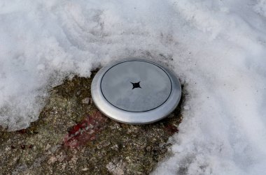 Kayadaki paslanmaz nokta pusula. Ana istikamet turistlerin tepenin zirvesine çıkmalarına yardımcı olacak. Kışın granit kaya karla kaplanır. Jeodezik işaret