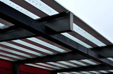 Galvanize metal kiriş çerçevesinden şeritli cam otobüs durağı. Tahta kaplama. Ulaşım için bekleyen yolcuları korumak için.