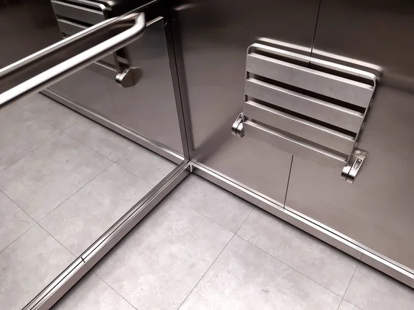 exit from the stainless steel elevator car. The elevator is equipped with a folding seat. when opened you can see the lattice, mesh floor and balcony railings. handle, handlebar