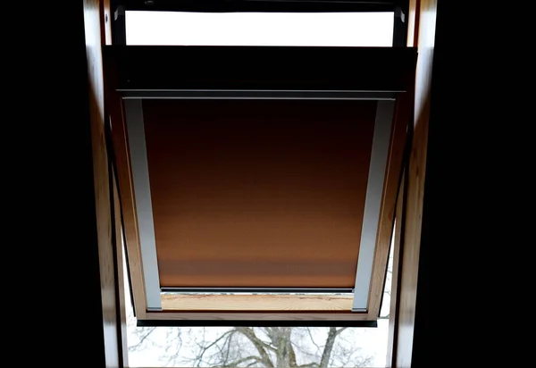brown sunroof blackout blinds. the window is half-open, the curtain drawn down turns day into night. black fiber or aluminum is woven into it. wooden paneling of the ceiling and lining