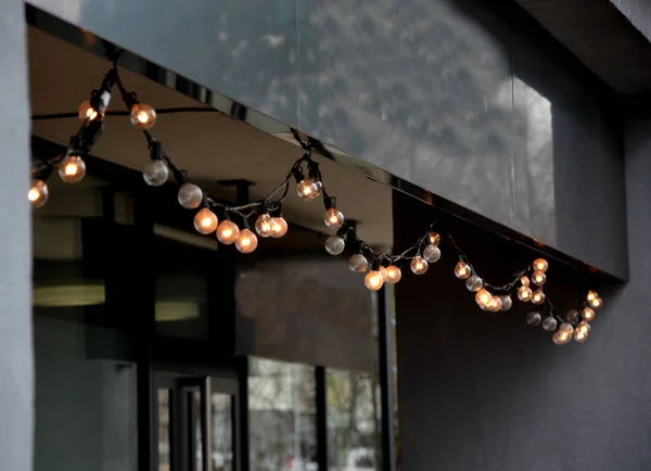 A big celebration in the restaurant terrace with light chains gives the evening atmosphere of a country or office cafe with black elegant wall coverings, glass, window,
