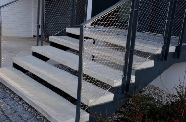 Taş duvar otoparkının yanında yüksek dayanıklılığa sahip dik bir merdiven inşa etmek. Ağır galvanize çelik zemin ızgarası ve parmaklıklar altında bile. Gabion onun üzerinde tel örgü örüyor. koridor, çiçek tarhı