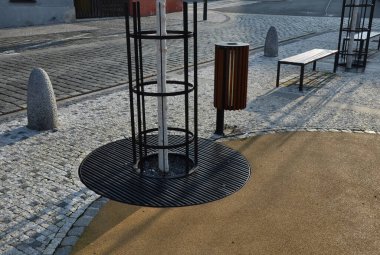 Kare şeklindeki silindirde taş bariyerler ve üstünde de bir yarımküre var. Granit kaldırımlar otoparkta duruyor. Zincirleme çit, yayalar ve taşlı araçlar kolonisine karşı.