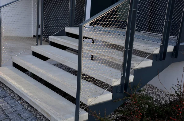 重い負荷亜鉛メッキ鋼床格子や手すりの下でも高い耐久性を持つ石壁駐車場による急な階段の建設 彼の上のギャビオンはワイヤーフェンスだ — ストック写真