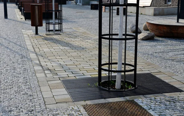 stock image dirty , cold rocking chair on pavement under tree in square. wooden deck chairs made of tropical wood for one person in park. snowing, cube, comfortable made of brown planks, slats steel frames, pine