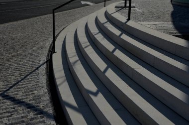 Beyaz taştan bir merdivenle arka ışıklandırması olan tek bir merdiven. Göz kamaştırıcı beyaz ve binaya yeni giriş. Asfalt kiremitler, ağaç