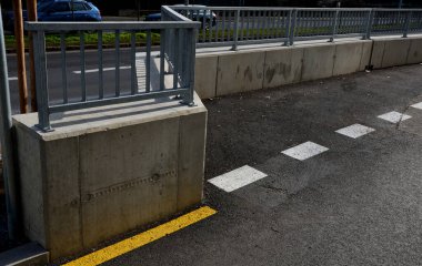 Yolun kenarında düşük galvanizli metal parmaklıklı beton duvar. Yoğun bir caddenin koruyucu bariyeri. Ahşap biçiminde beton döküm. Yol ve asfalttaki yol çizgileri. yeni tamamlandı