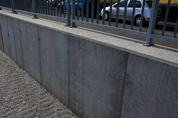 道路脇の低亜鉛メタル手すりのコンクリート壁 忙しい通りの保護バリア 木製の型枠にコンクリート鋳造 アスファルト上の道路や道路の線 新しく完成した — ストック写真