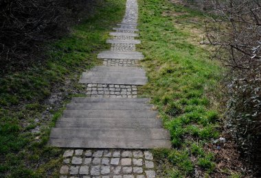 Parktaki ahşap basamaklar ve çimenlikteki kaldırımlar. Merdiven kirişleri örgü ile kaplı. Perdeler ıslak ve ıslakken tabanlar o kadar kaymaz, parmak, bahçıvan
