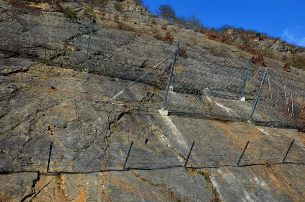 用深嵌在岩石中的钢网加固斜坡 排成倾斜的栅栏 在山口上方有巨大的网状物 将挡住侵蚀的大石头和坠落的石头 — 图库照片