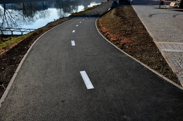 embankment with a new bike path right next to the meanders of the river. it copies its flow and encourages cyclists to continue along the water, park bench