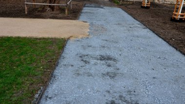 Kum tekeri. Bahçe el arabası bir işçi taşır ve park, orman ve toprak yolu onarmak için bej çakıl yığınlarının üzerine dökülür. Erozyon, yenilenmesi gereken çakılları alıp götürür.