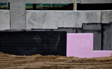 Yeraltı katının çevresinde polistiren plakalar olan termal yalıtım. Kaynamış folyoyla suya ve neme karşı izolasyon. Binanın etrafını doldur. Toprak serpme temeli