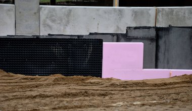 Yeraltı katının çevresinde polistiren plakalar olan termal yalıtım. Kaynamış folyoyla suya ve neme karşı izolasyon. Binanın etrafını doldur. Toprak serpme temeli