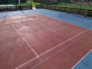 Okuldaki top oyunları için çok işlevli açık hava oyun alanı. Yeşil yapay çim, çizgileri olan plastik bir halıdan. Basketbol potaları ve futbol golleri. Ağı ve korkulukları çevreleyen, 