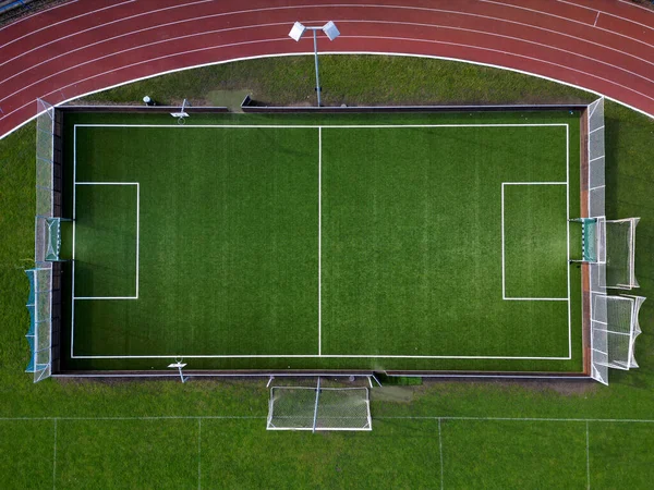 有多条车道的跑道的体育场 在椭圆形的内部有一个小足球场 里面有网球场和带盾屏障的手球 合成草皮 从顶部看 — 图库照片
