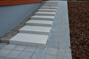 Tam yanında kademeli rampa olan büyük uzun merdivenler. Gri fayans binası ve merdiven boyunca uzanan yamaç. ağaç kabuğu gübresi.